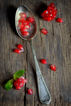 Ripe pomegranate and spoon on wooden tableの写真素材