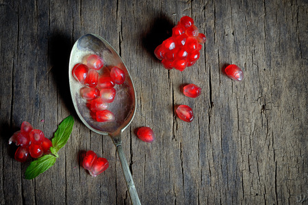 Ripe pomegranate and spoon on wooden tableの写真素材