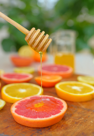 Slices of grapefruit, clementine, orange and honeyの写真素材