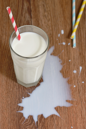 Milk spilled from glass on wooden tableの写真素材