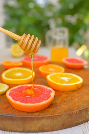 Slices of grapefruit, clementine, orange and honeyの写真素材