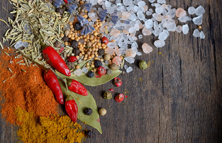 Colorful spices and herbs on old woodの写真素材