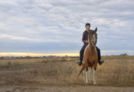 Happy teenager boy with horse on fieldの写真素材