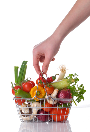 Raw vegetables and hand  in basket isolated on whiteの写真素材