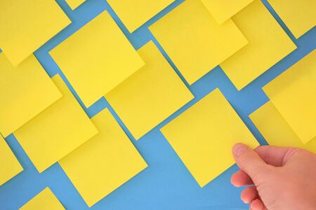 Hand holding post-it note on blue boardの写真素材