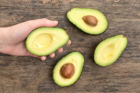 Slices Of Avocado Cut In Half On Wooden Tableの写真素材