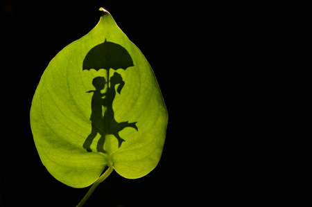 Conceptual Silhouette Of Romantic Couple Embracing holding an umbrellaの写真素材