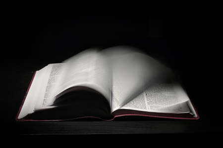 An Open Holy Bible Moving Pages on Dark Bckgroundの写真素材