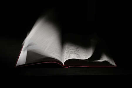 An Open Holy Bible Moving Pages on Dark Bckgroundの写真素材