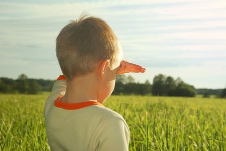 happy young boy looking horizon and dreaming on green field grassの写真素材