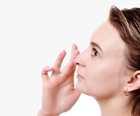 Young beautiful girl applying cream on her faceの写真素材