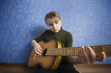 dark grunge style rock star holding a guitar  on floor sits