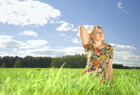 beautiful young woman on field of green grass in summer timeの写真素材