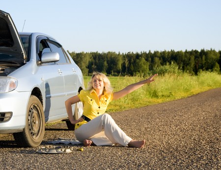 Girl standing by the side of the road with the hood of her car open signaling problems with the carの写真素材