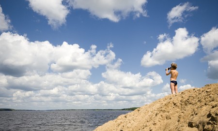 child looking through binoculars to horizon on riverの写真素材