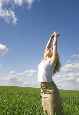 Young happy woman in field under blue skyの写真素材