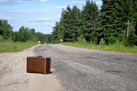 One old suitcase left on a dirt roadの写真素材