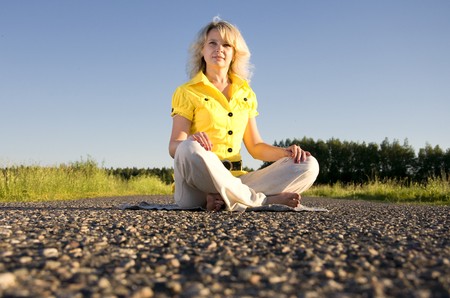 girl meditates on highway middle in rural outdorsの写真素材