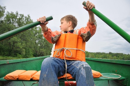 Young man rowing a boat on the river.の写真素材