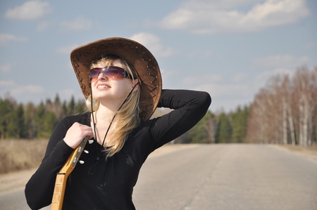 The beautiful blonde with a guitar on the roadの写真素材