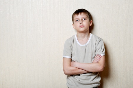 upset small boy stands against a wallの写真素材