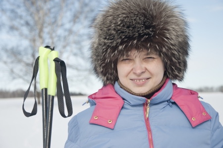 Woman tourist skier in snowy forest with ski polesの写真素材