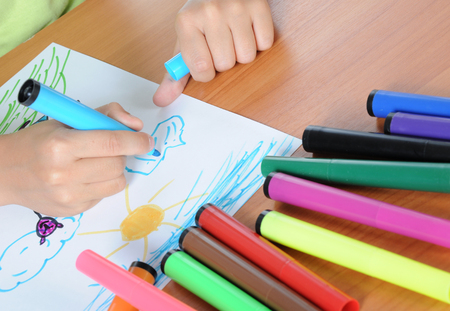 Unrecognizable child drawing picture on paper by colours pencilの写真素材