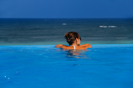 Woman in the infinity pool enjoying the ocean view