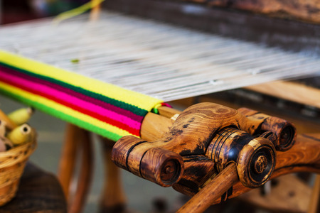 A closeup image of an old weaving Loom and thread of yarn.