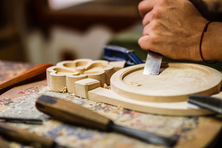 Carpenter hand carving wood with care. Hand with tool blured in motion.の写真素材