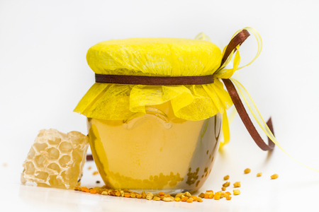 Herbal honey in jar with small honeycomb and herbs isolated on white backgroundの写真素材