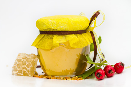 Herbal honey in jar with small honeycomb and herbs isolated on white backgroundの写真素材