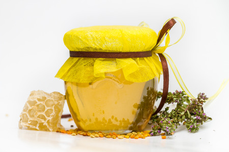 Herbal honey in jar with small honeycomb and herbs isolated on white backgroundの写真素材