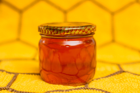 Jar of honey on honeycomb textile. Herb natural honey.の写真素材
