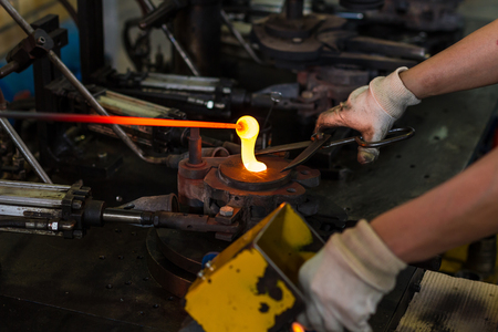 Glass blower forming beautiful piece of glass. A glass crafter is burning and blowing an art piece.の写真素材