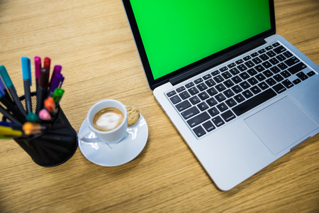 Side view of laptop with blank green screen on table in modern office. Picture proper for keying...