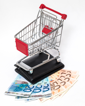 Shopping cart with black wallet and money isolated on whiteの写真素材