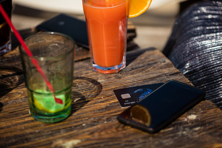 Orange cocktail on rustic wooden table.Alcohol orange daiquiri and mint cocktail, and credit card on...