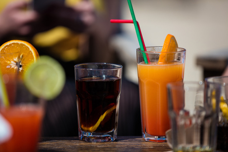 Alcohol orange daiquiri and cuba libre cocktail on beach bar rustic wooden table.