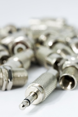 Pile of Connectors on white background, focus is on audio mono adapter and the background is blur.