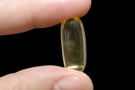 Hand holding a pill on black backgroundの写真素材