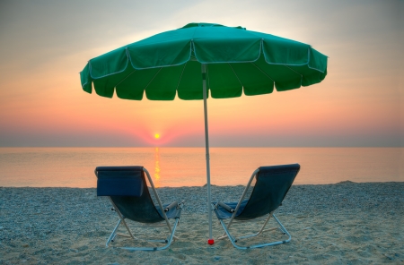 Chairs and umbrella on a beach at sunriseの写真素材