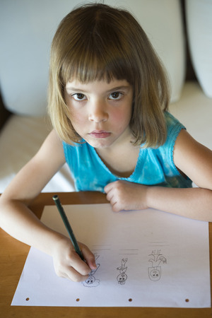 Little girl drawing at home sitting on sofaの写真素材