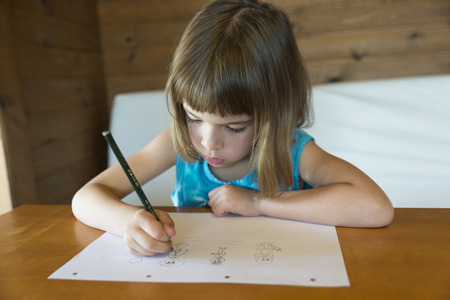 Little girl drawing at home sitting on sofaの写真素材