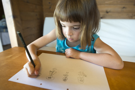 Little girl drawing at home sitting on sofaの写真素材