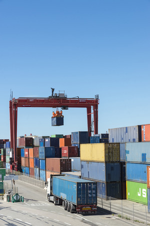 Barcelona, Spain - May 23, 2014   Cargo container hanging on a crane in the Barcelona Harbor  In the picture a truck carrying containers which is entering the terminal appears Cargo container hanging on a crane in the Barcelona Harborのeditorial素材