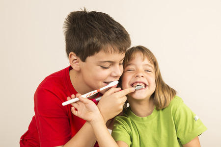 Funny portrait of a young girl and a young boy brushing each other 