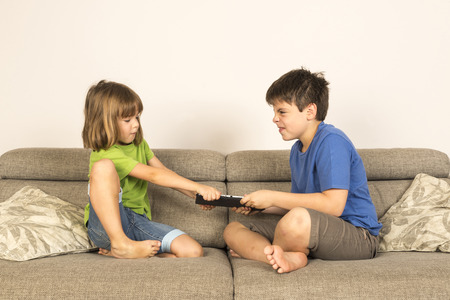 Kids arguing for playing with a digital tablet on a sofa  の写真素材