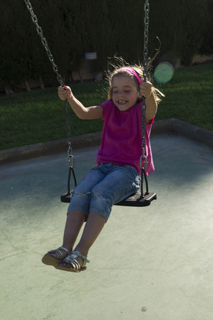 Little girl swinging on a playgroundの写真素材