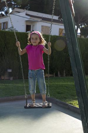 Little girl swinging on a playgroundの写真素材
